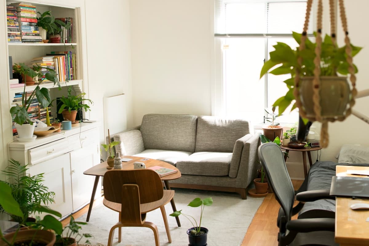 Un salon meublé et lumineux, avec des plantes vertes et un espace de travail.